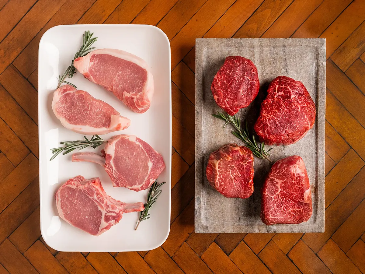 Chuletas de cerdo y medallones de res sobre bandeja y piedra